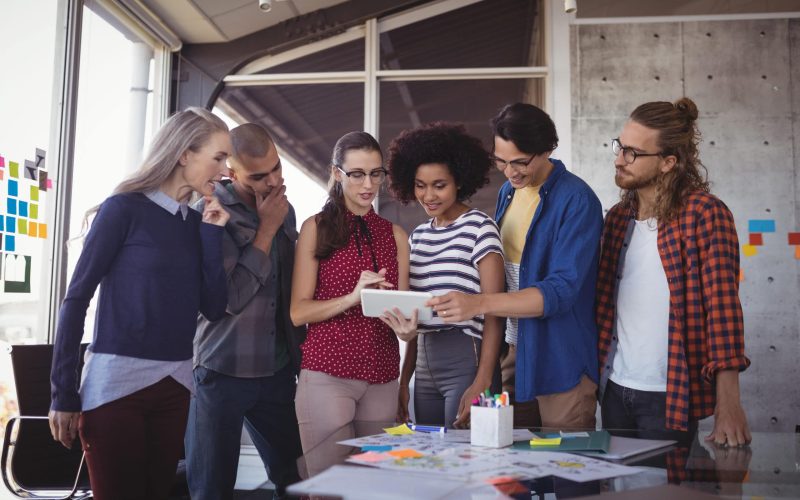 Group of creative business people using digital tablet while planning in creative office